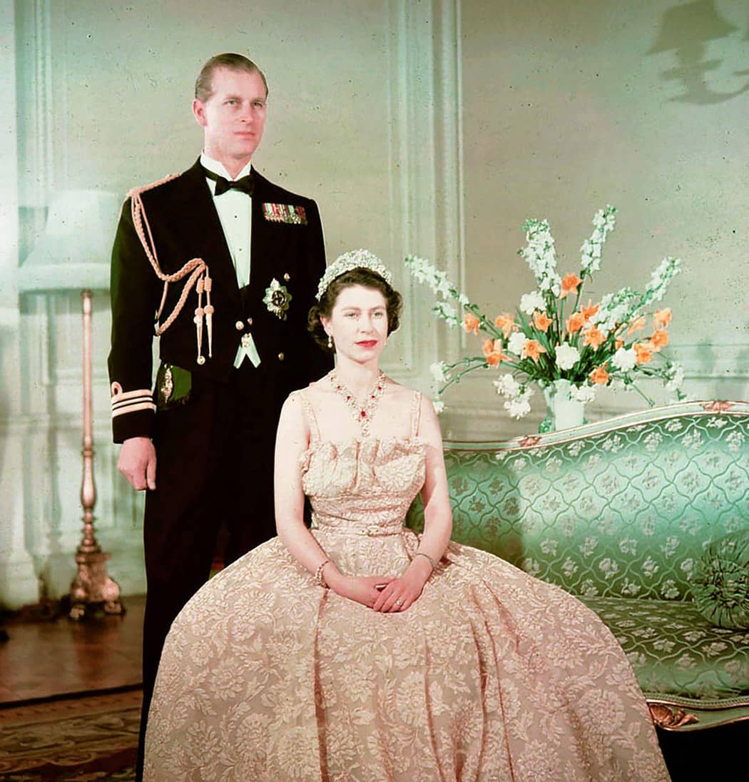 Ancienne photographie présentant la reine Elizabeth II assise, le prince Philip se tient debout derrière elle